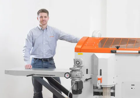Jake standing beside a woodworking machine in a photo studio